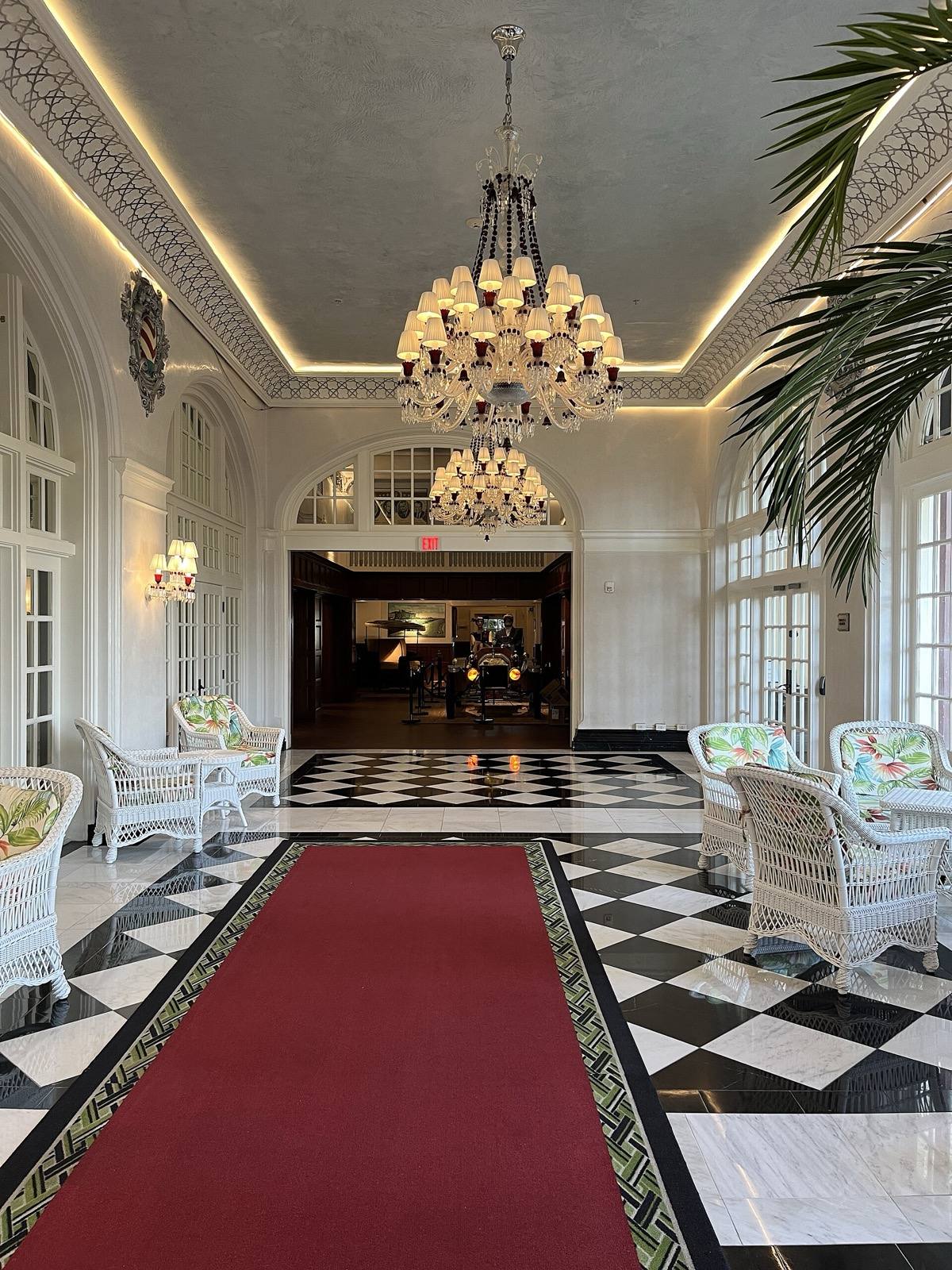 The lobby of the Grand Galvez: chandeliers, a red runner and a black and white floor